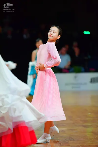Dancesport competitor: Female dancer in foreground: voluminous white dress with large red ruffles