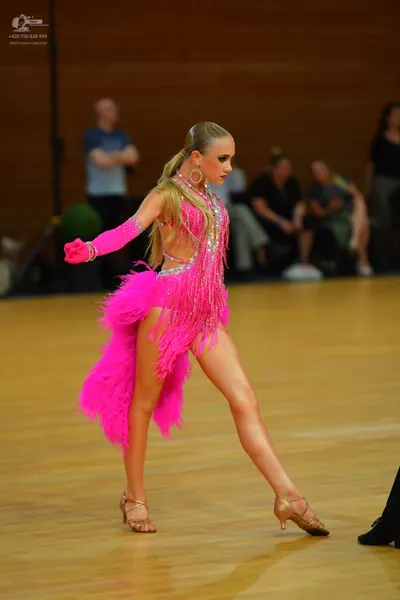 Dancesport competitor: Female** - Red Latin dress with a flowing, ruffled skirt heavily embellished wit