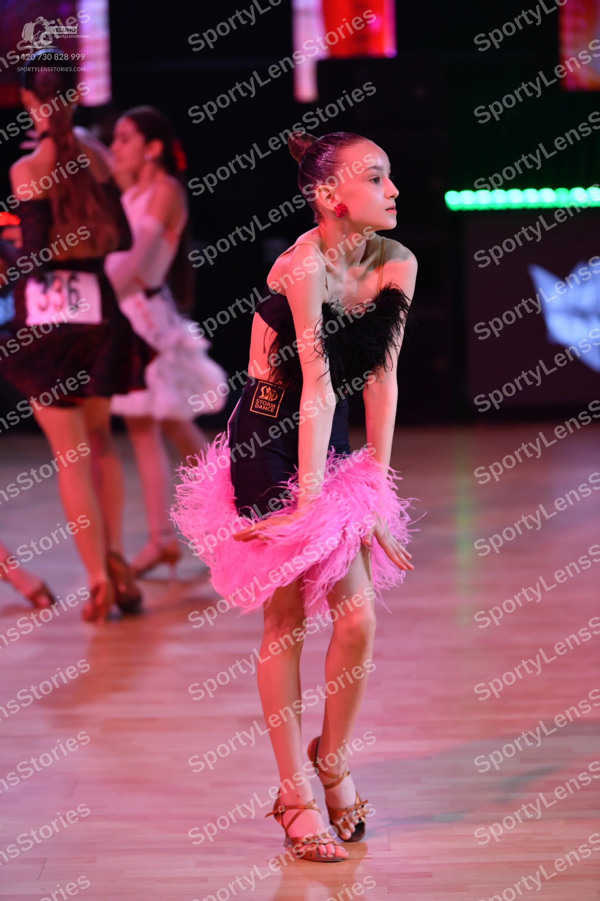 Dancesport competitor: Dancer on left: dark brown or black latin dress with shiny accents