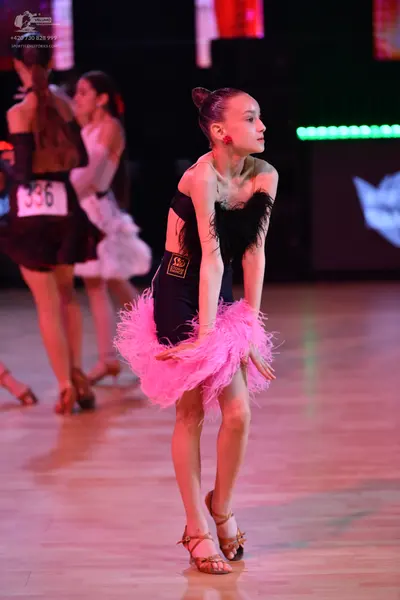 Dancesport competitor: Dancer on left: dark brown or black latin dress with shiny accents