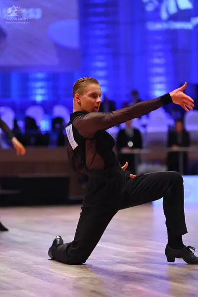 Dancesport competitor: Male dancer: black long-sleeved top with sheer mesh sleeves and side panels, bla