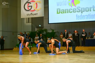 Dancesport competitor: All four dancers are wearing matching black, form-fitting latin dance costumes (