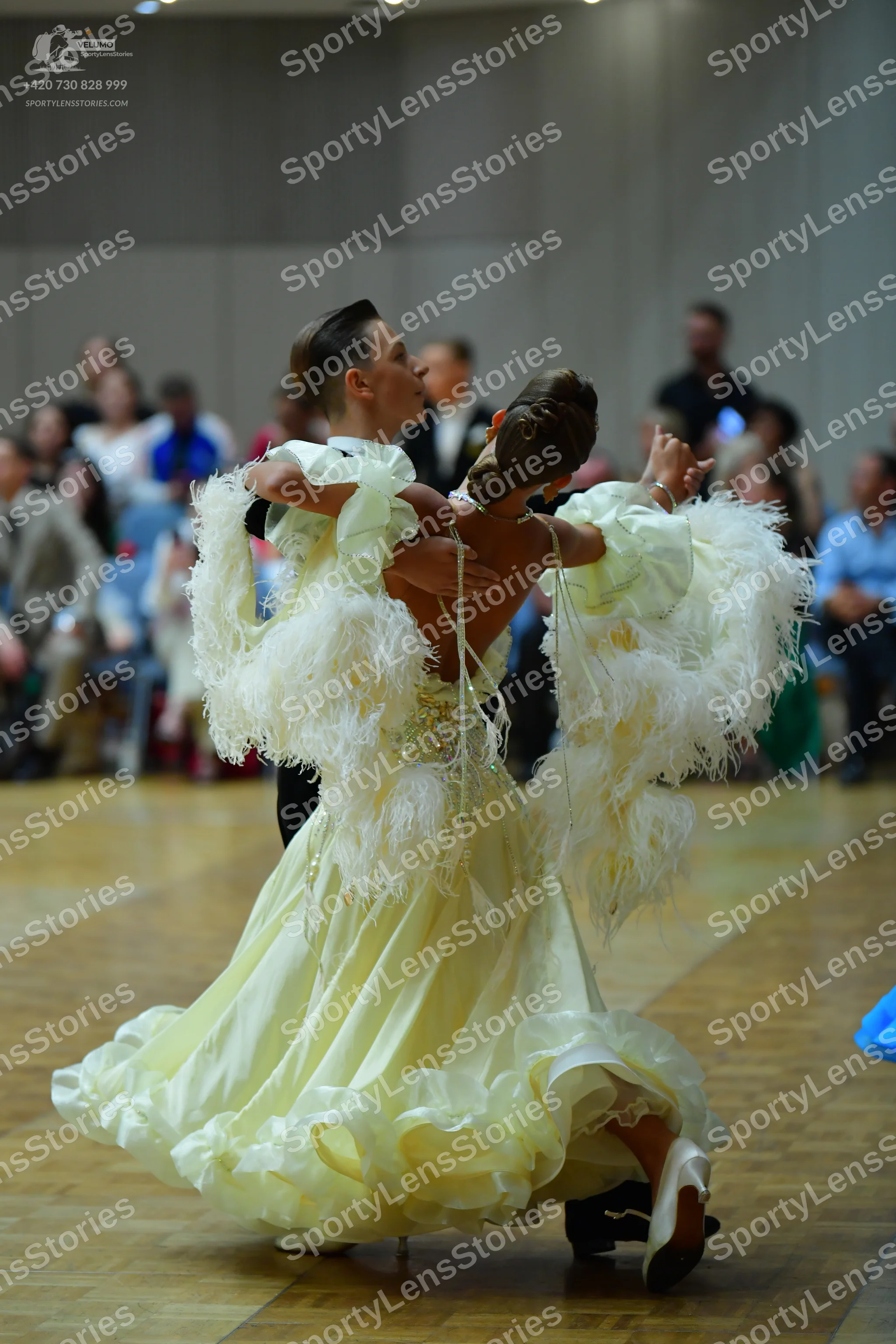 Dancesport competitor: Female dancer: pale yellow/cream voluminous ballgown with a ruffled skirt and la