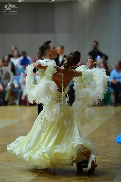Dancesport competitor: Female dancer: pale yellow/cream voluminous ballgown with a ruffled skirt and la