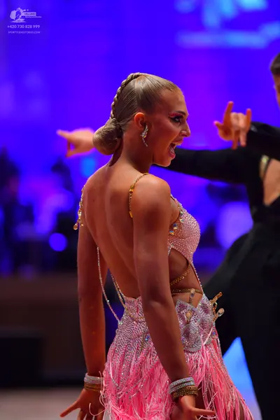 Dancesport competitor: Female dancer: pink Latin dress with sequins, long pink fringe, and gold-colored