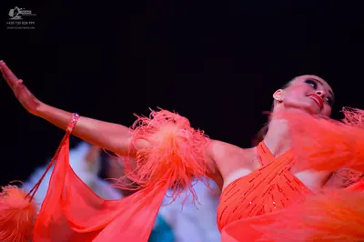 Dancesport competitor: Female dancer: bright orange Latin dance dress featuring rhinestone embellishmen