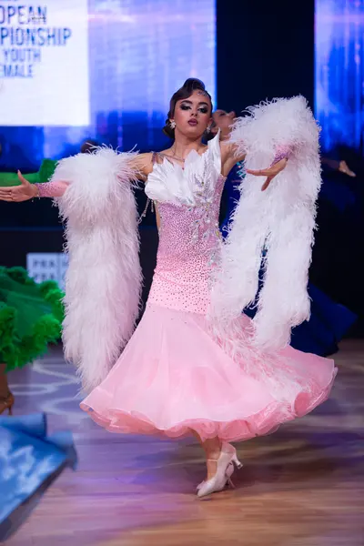 Dancesport competitor: Female dancer: pink ballroom gown with a sequined bodice and a voluminous tulle 
