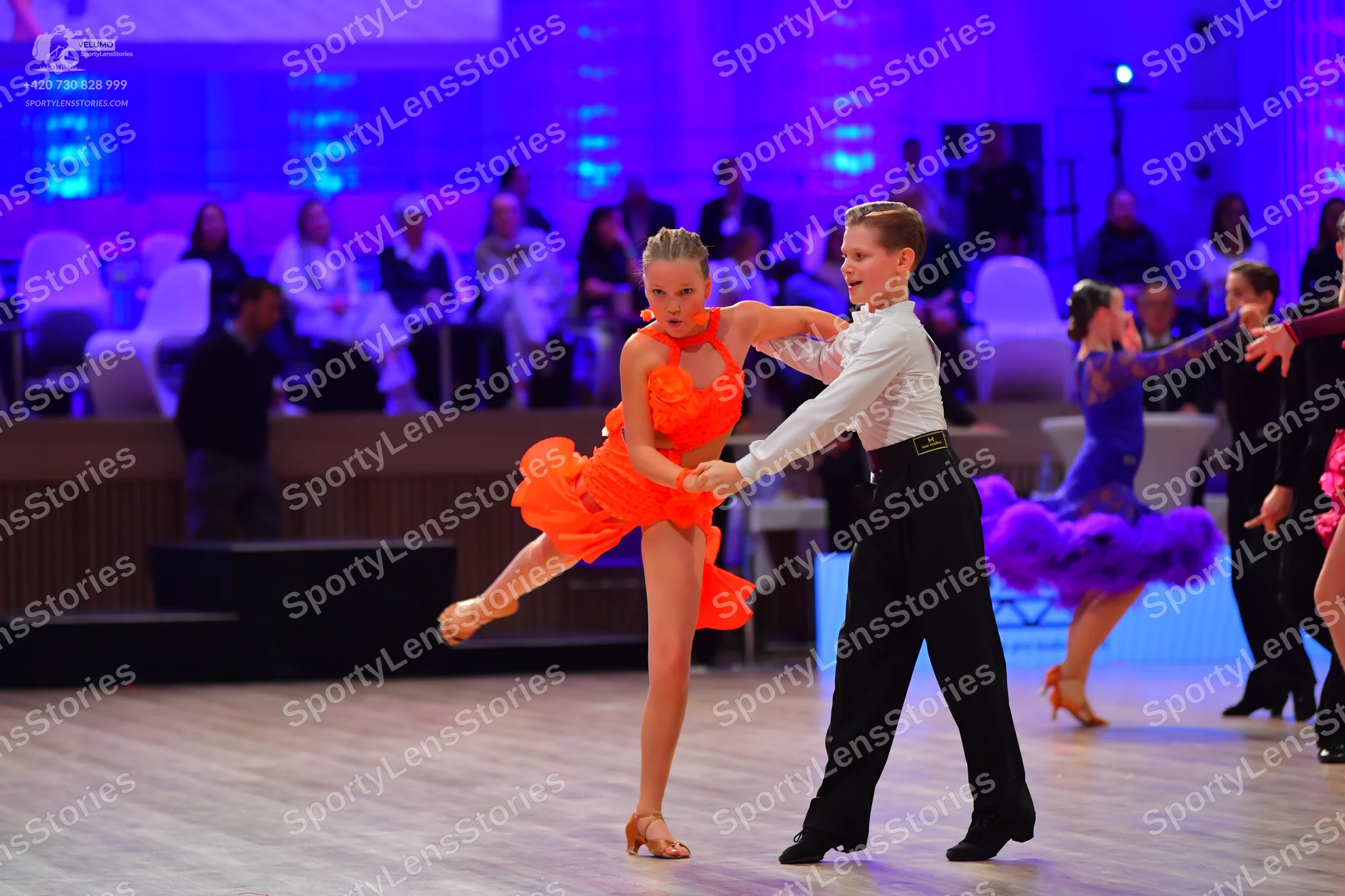 Dancesport competitor: Male dancer in foreground: white long-sleeved shirt and black trousers