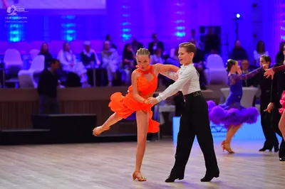 Dancesport competitor: Male dancer in foreground: white long-sleeved shirt and black trousers