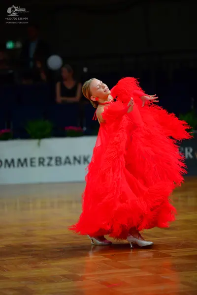 Dancesport competitor: Female dancer: large, voluminous red ballgown with many layers of ruffled, feath