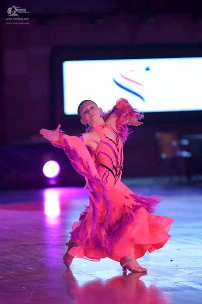Dancesport competitor: Female dancer: bright pink latin dress with black sequin detailing and dark purp