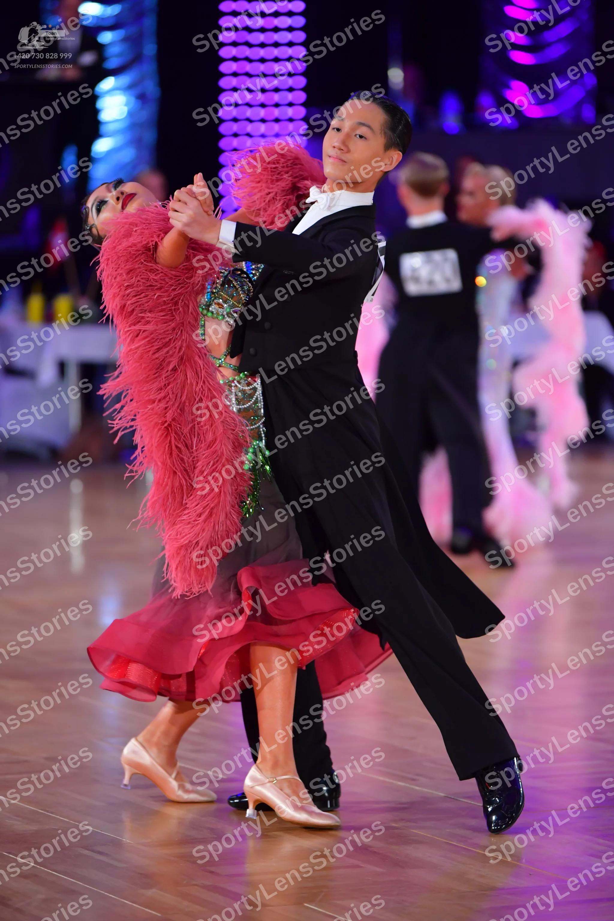 Dancesport competitor #142: Foreground male dancer: black suit with white shirt collar and black dance shoes