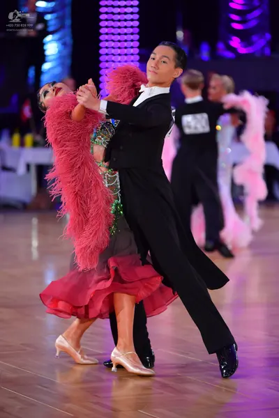 Dancesport competitor #142: Foreground male dancer: black suit with white shirt collar and black dance shoes