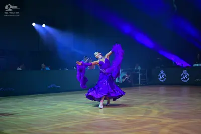 Dancesport competitor: Female dancer: purple ballgown with a large, voluminous skirt and long, flowing 