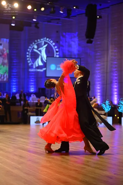Dancesport competitor: Female dancer: bright red ballroom gown with a voluminous, ruffled skirt made of