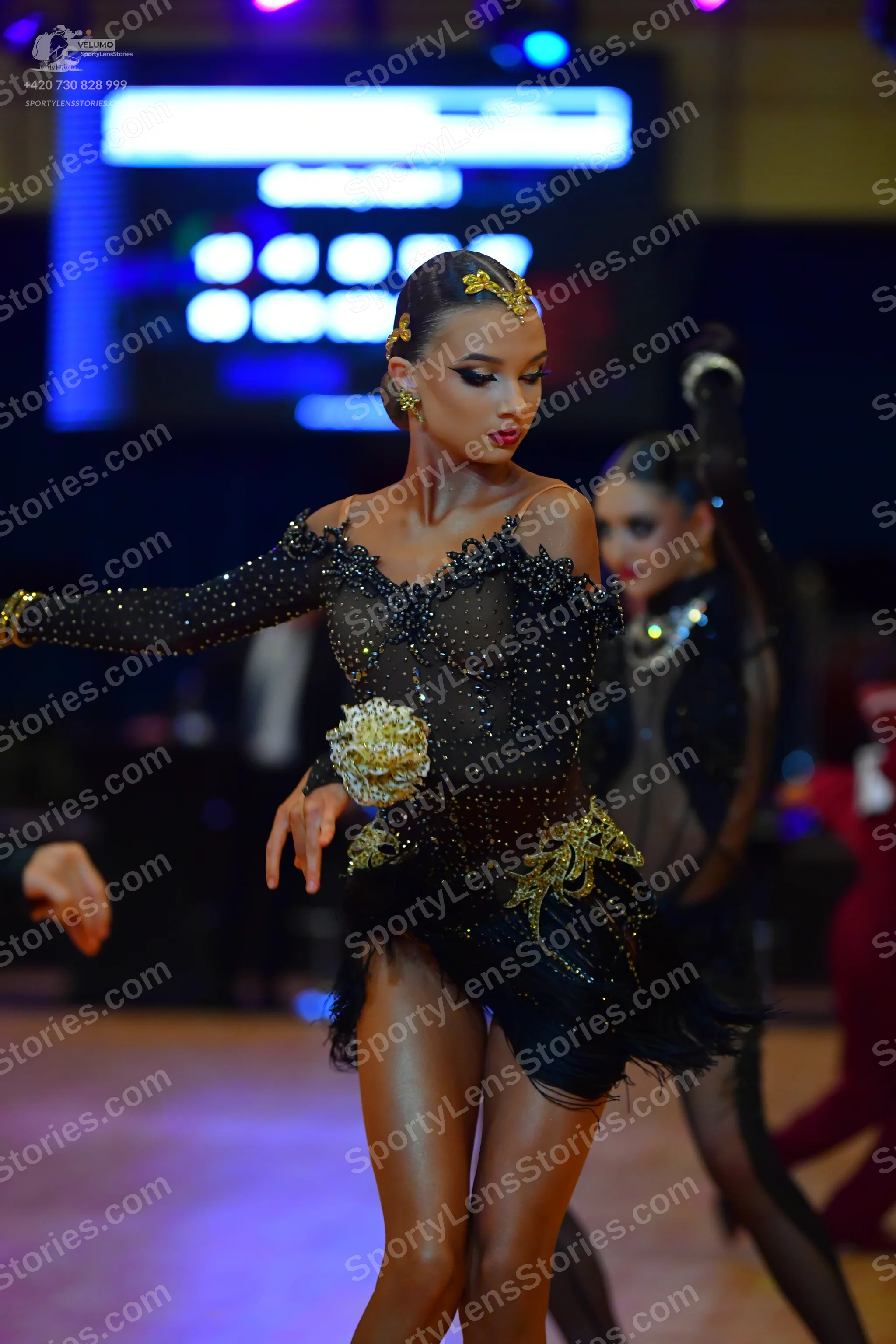 Dancesport competitor: Female dancer: black long-sleeved Latin dress covered in small sequins, featurin