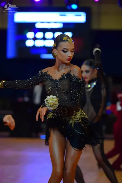 Dancesport competitor: Female dancer: black long-sleeved Latin dress covered in small sequins, featurin