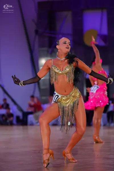 Dancesport competitor #10, #17: Female dancer: gold sequined Latin dance top and skirt with long gold fringe, lo