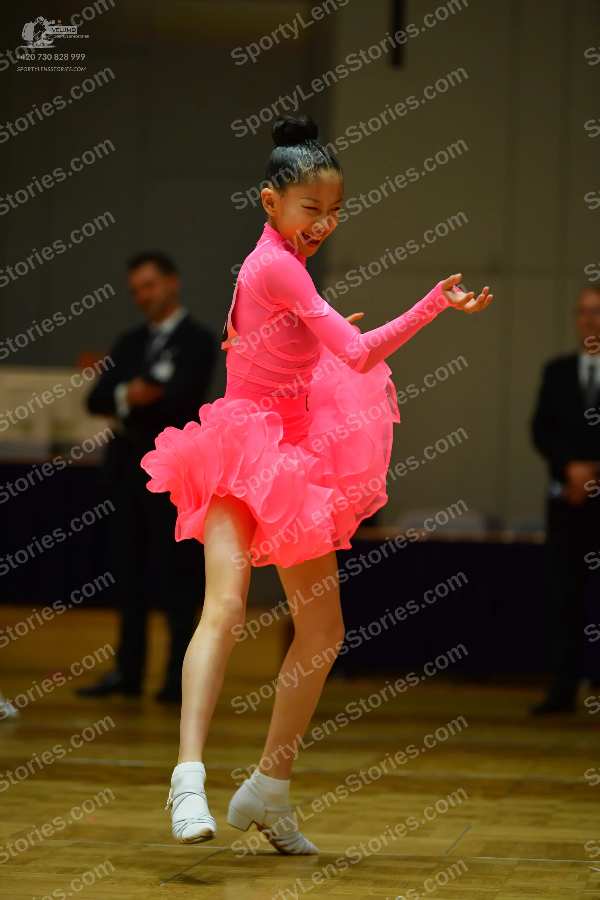 Dancesport competitor: Female dancer: bright pink long-sleeved Latin dance dress with a multi-layered r