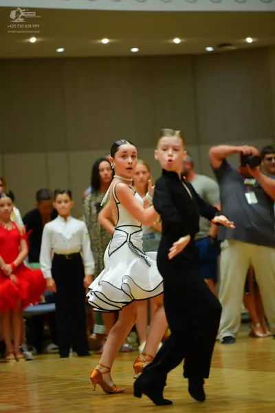 Dancesport competitor: Main female dancer: white latin dress with black trim and a flared skirt