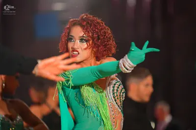 Dancesport competitor: Female dancer: bright green Latin dress with sequins, beads, and long bright gre