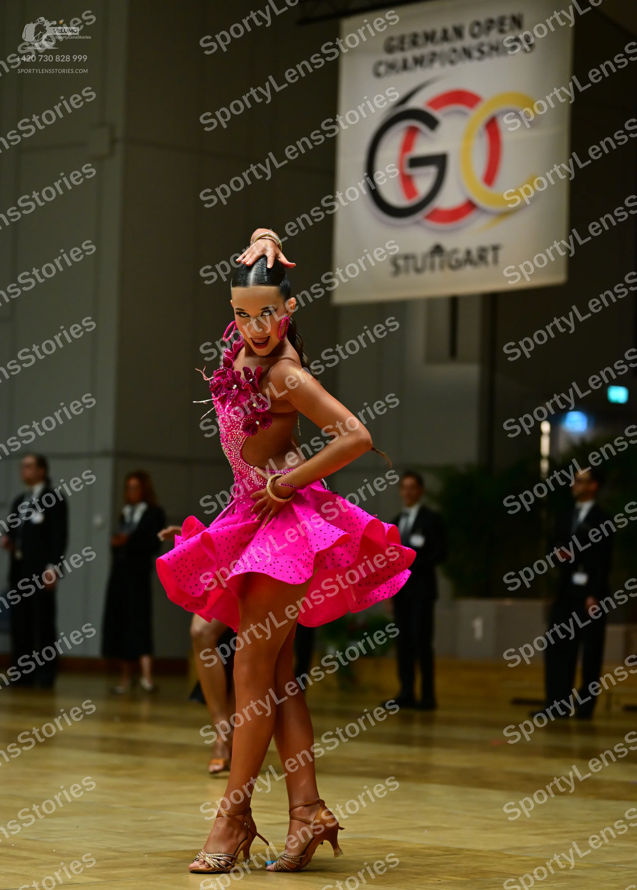 Dancesport competitor: Main female dancer: bright pink Latin dance dress with a flared, ruffled skirt a
