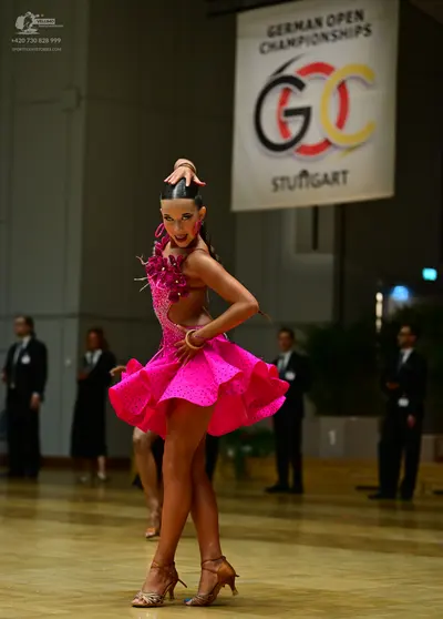 Dancesport competitor: Main female dancer: bright pink Latin dance dress with a flared, ruffled skirt a