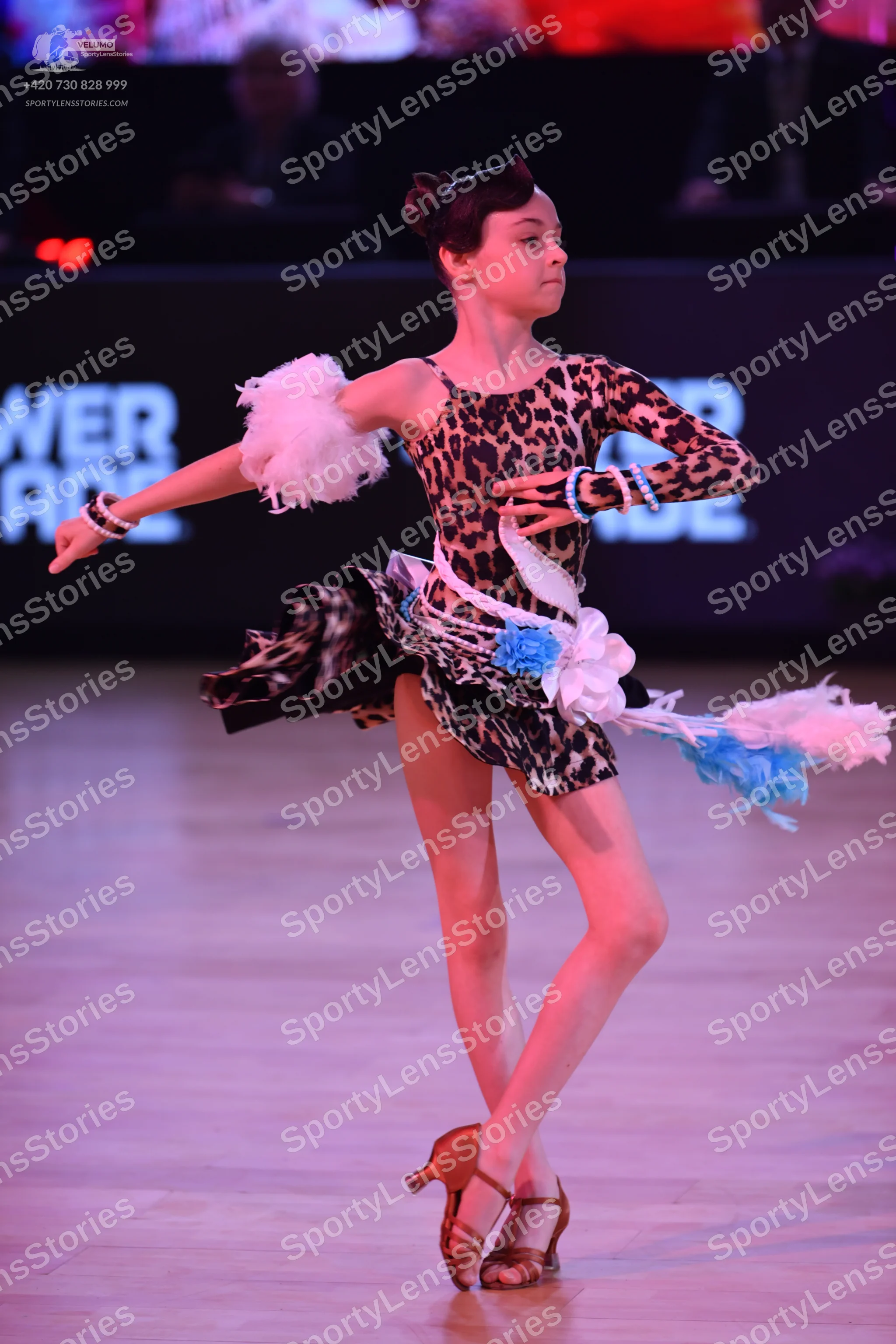 Dancesport competitor: Female dancer: leopard print Latin dress with long sleeves, featuring white and