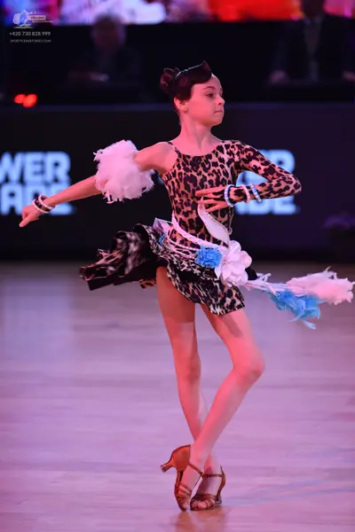 Dancesport competitor: Female dancer: leopard print Latin dress with long sleeves, featuring white and 