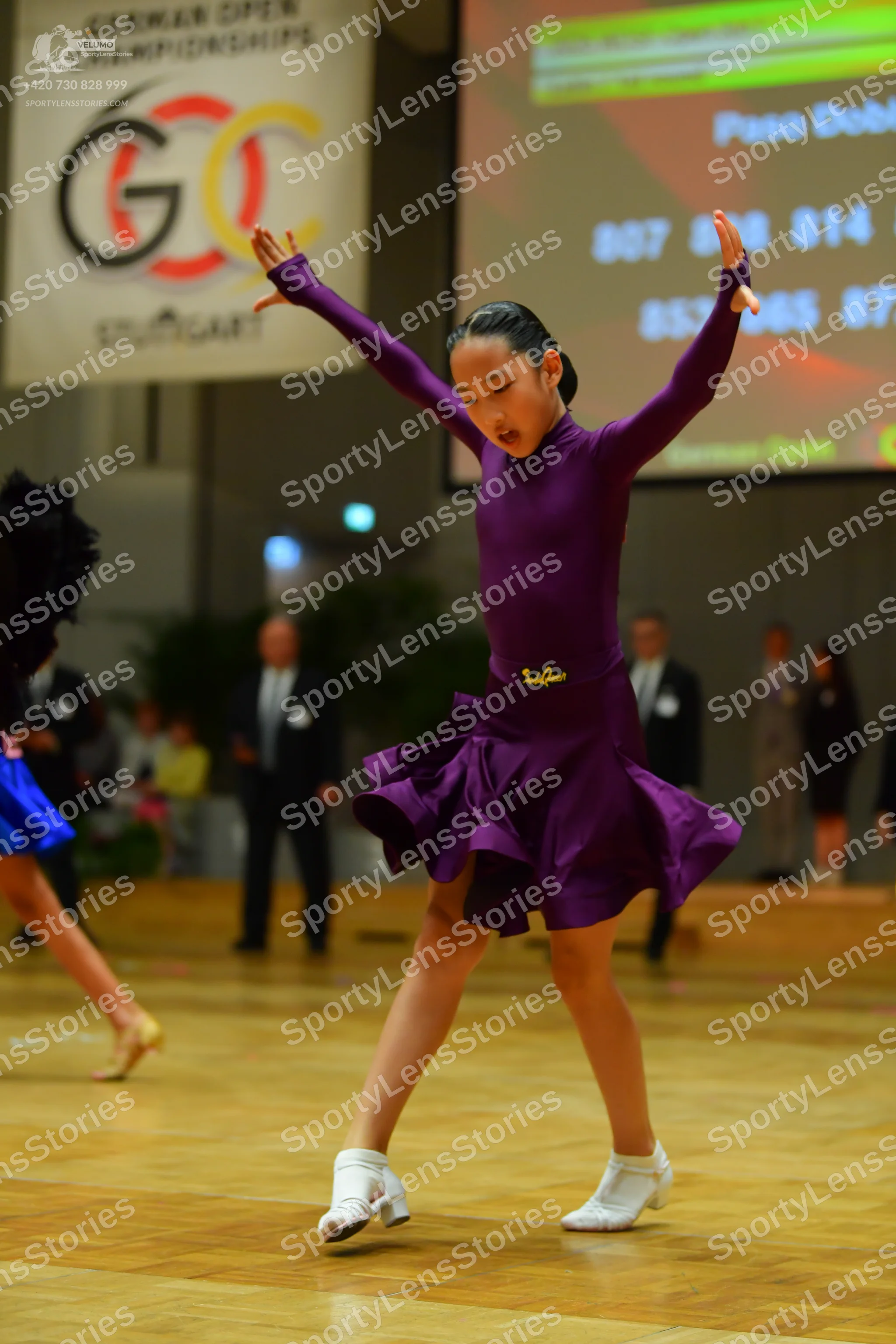 Dancesport competitor: Female dancer (main): purple long-sleeved latin dress with a flared, ruffled ski