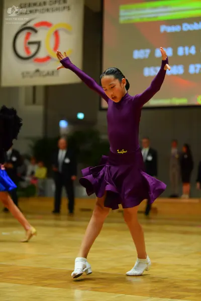 Dancesport competitor: Female dancer (main): purple long-sleeved latin dress with a flared, ruffled ski