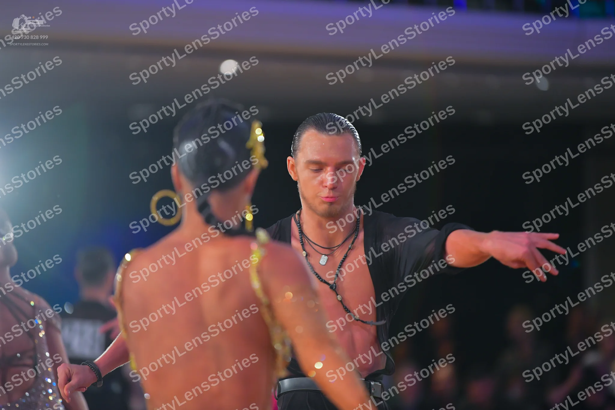 Dancesport competitor: Male dancer: black, loose-fitting, unbuttoned Latin-style shirt and a black neck