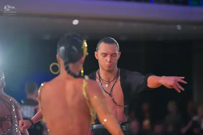 Dancesport competitor: Male dancer: black, loose-fitting, unbuttoned Latin-style shirt and a black neck