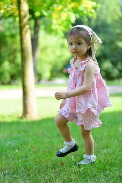 Dancesport competitor: Female dancer: pink and white gingham ruffled romper, white lace headband, white