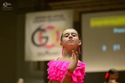 Dancesport competitor: Female dancer: bright pink dress with multiple layers of ruffles