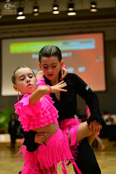 Dancesport competitor: Female dancer: bright pink two-piece Latin dance costume featuring a ruffled cro