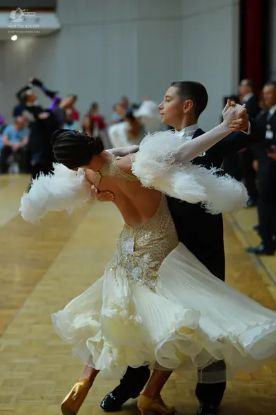 Dancesport competitor: Female dancer: white ballroom gown with a sequined bodice and a large, voluminou