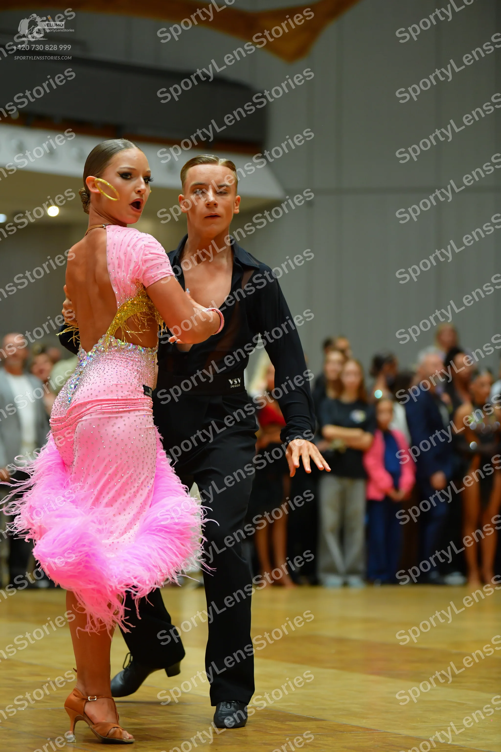 Dancesport competitor: Female dancer: pink Latin dress with a sequined bodice and a voluminous pink fea