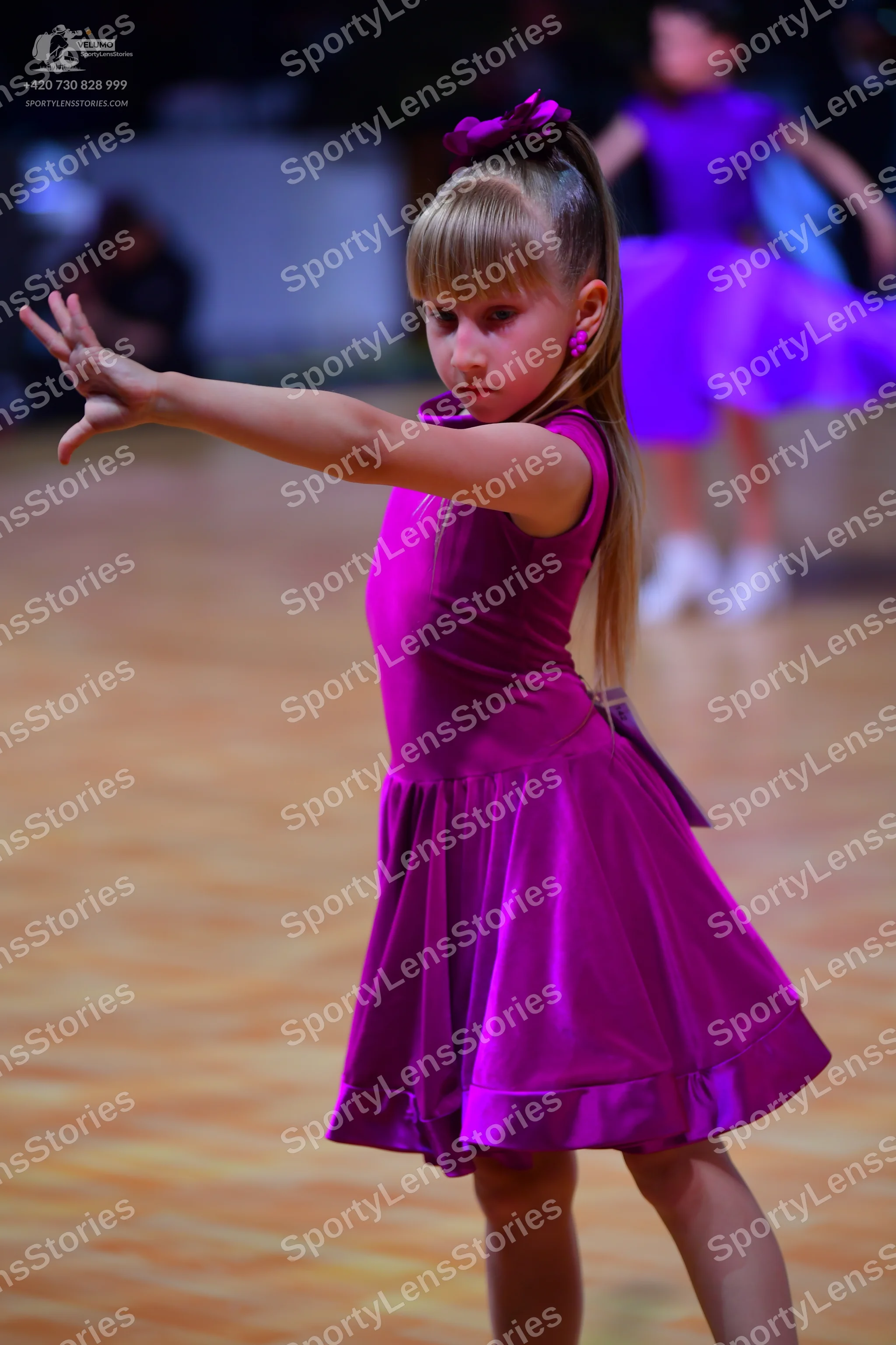 Dancesport competitor: Female dancer in foreground: magenta, satin-like, sleeveless dress with a full s
