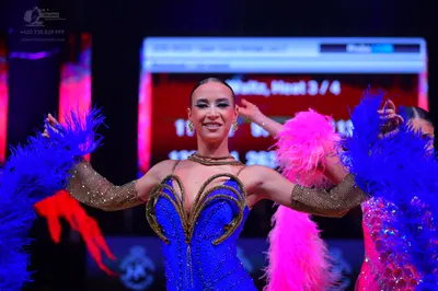 Dancesport competitor: Female dancer in center: blue sequin Latin dress with gold/bronze-colored embroi