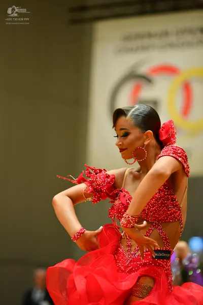 Dancesport competitor: Female dancer: red latin dress with sequins and voluminous ruffled skirt, access