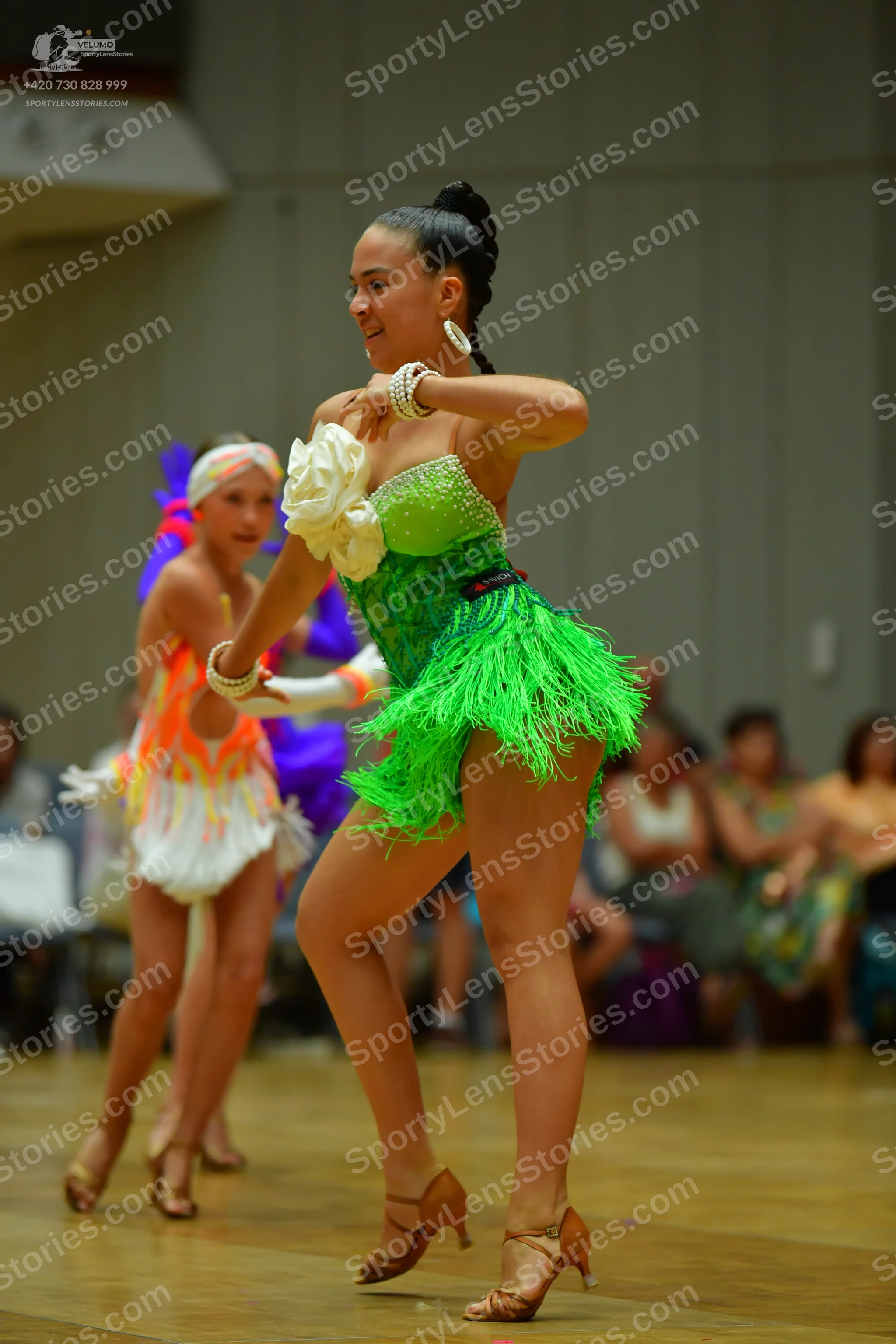Dancesport competitor: Female dancer 1: green latin dress with sequin top and green fringe skirt, weari