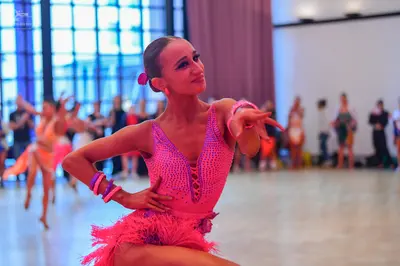 Dancesport competitor: Main female dancer: pink/magenta Latin dress with a sequined bodice and a fringe