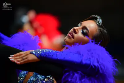 Dancesport competitor: Female dancer: royal blue latin dress with sequins and large blue feather trim, 