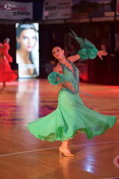Dancesport competitor: Female dancer in foreground: green ballroom dress with sequin/beaded bodice and 