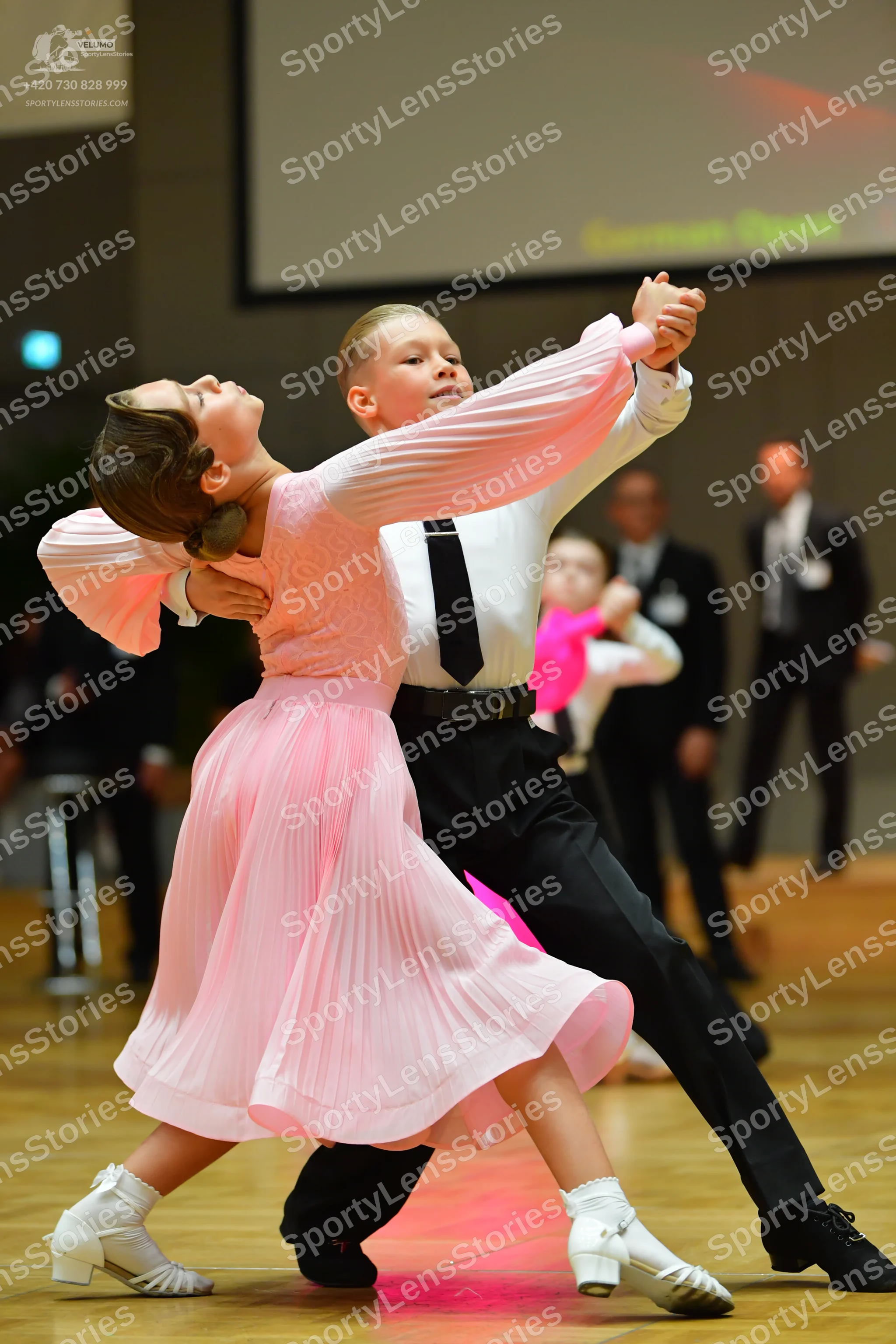 Dancesport competitor: Female dancer: light pink long-sleeved ballroom dress with a pleated skirt and w