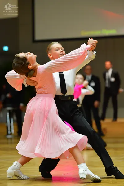 Dancesport competitor: Female dancer: light pink long-sleeved ballroom dress with a pleated skirt and w