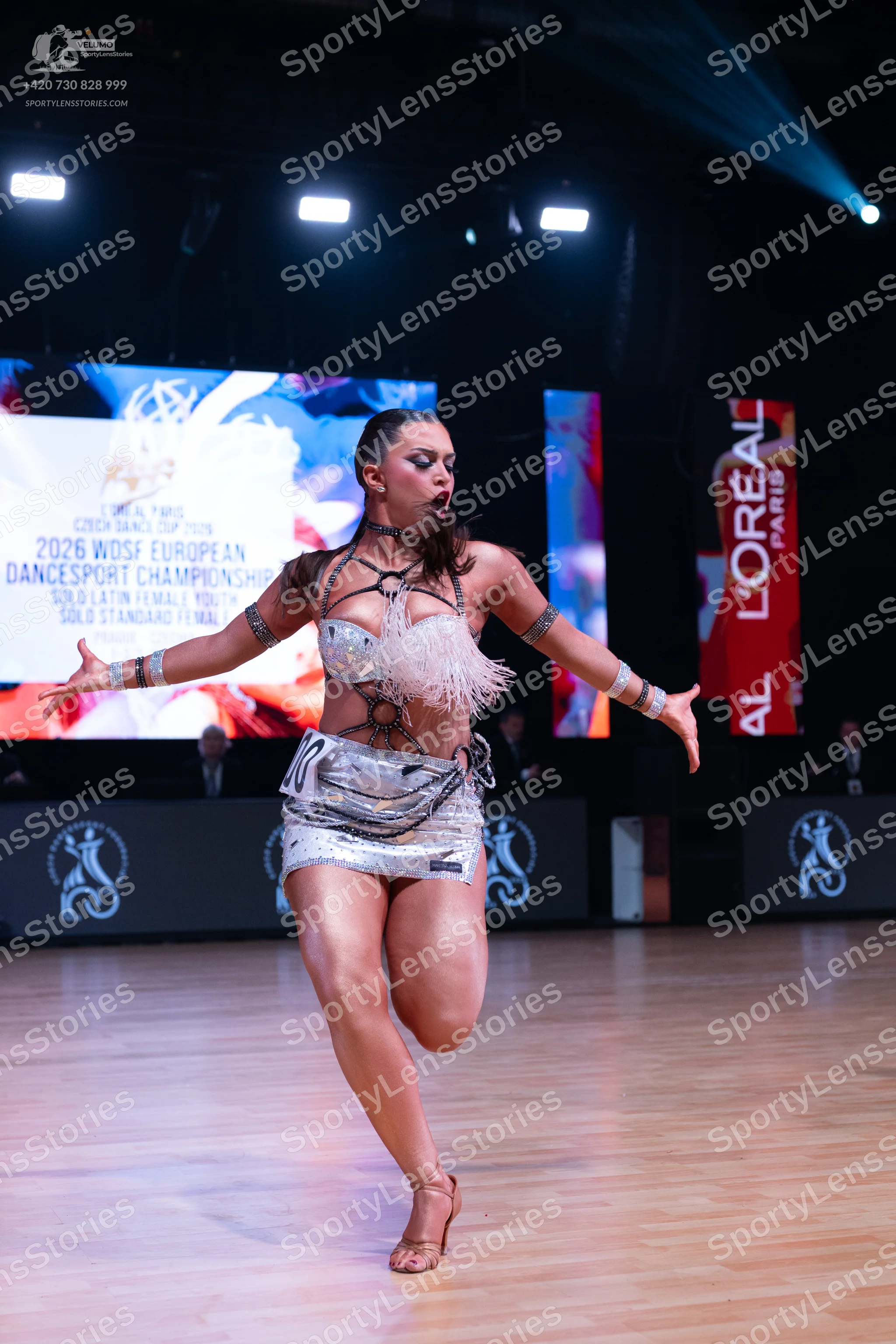 Dancesport competitor: Female dancer: silver metallic Latin dance costume with a sequined bra top featu