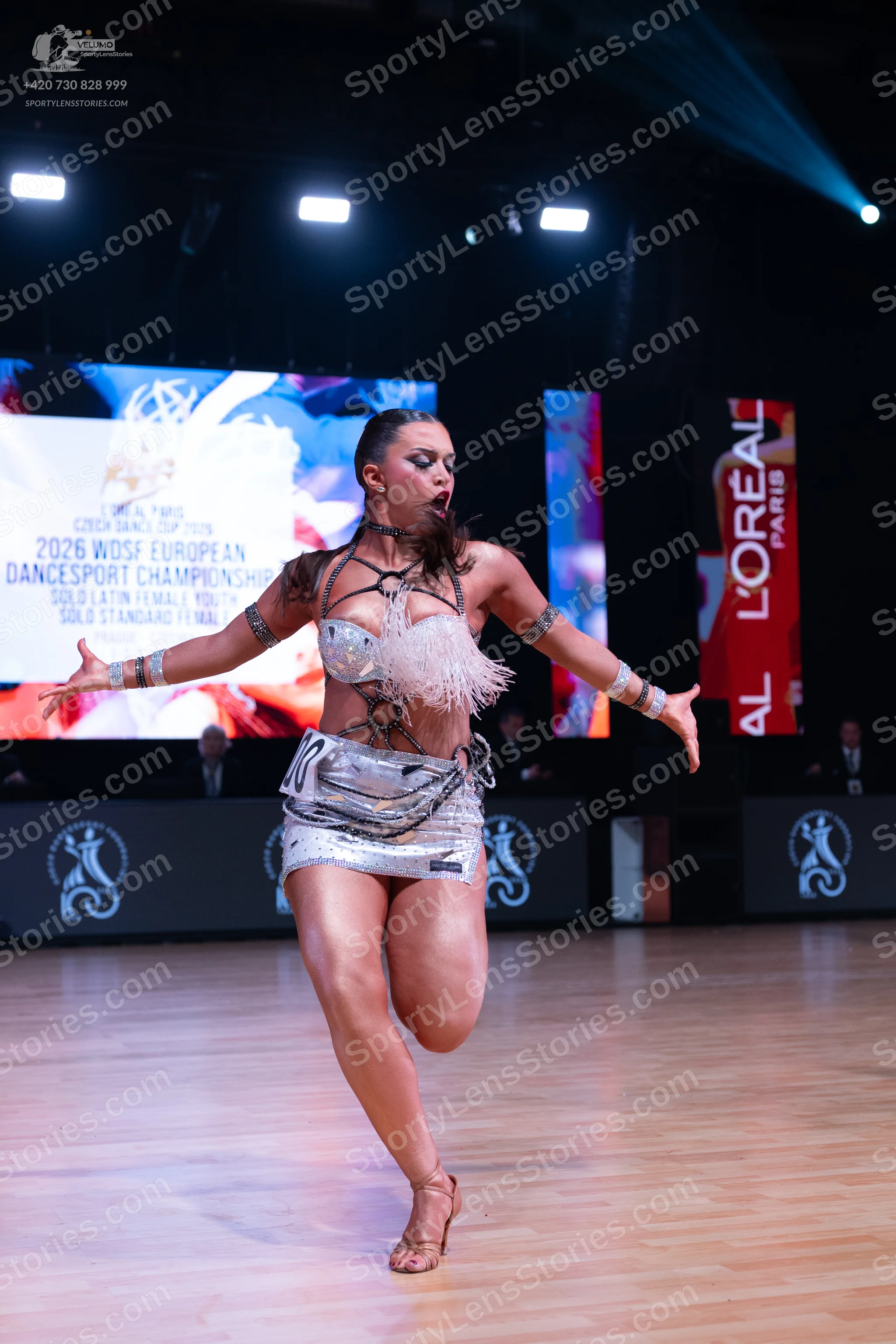 Dancesport competitor: Female dancer: silver metallic Latin dance costume with a sequined bra top featu