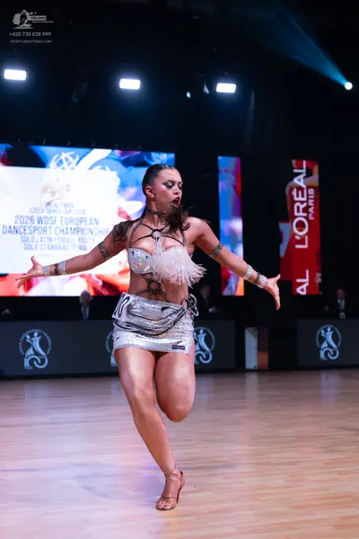 Dancesport competitor: Female dancer: silver metallic Latin dance costume with a sequined bra top featu